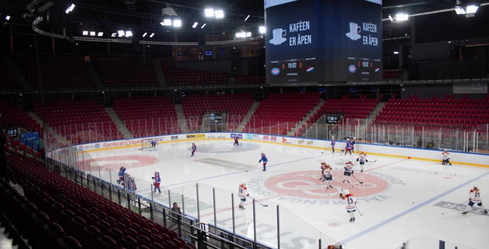 En ishockeybane omringet av røde tribune stoler. Det er 11 Vålerenga spillere og 10 Hasle 