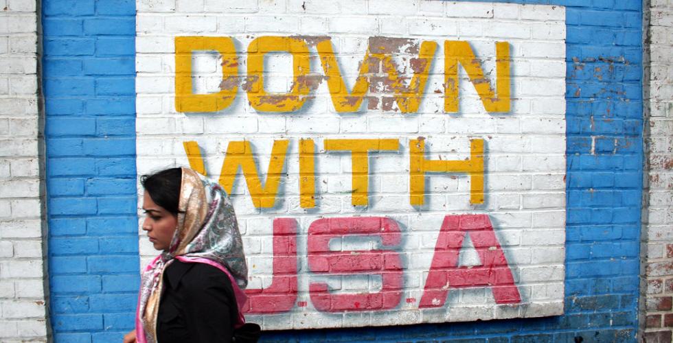 Kvinne går forbi veggmaleri med ordene "Down with USA"