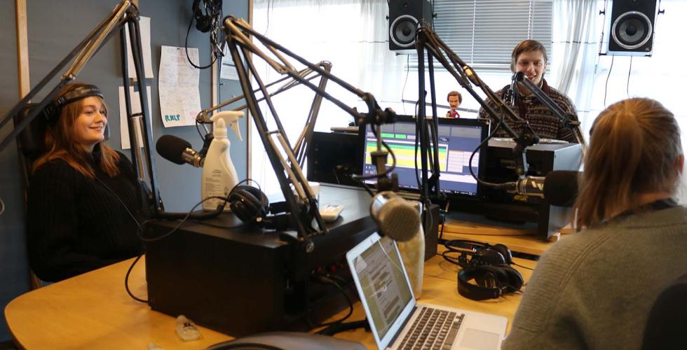 Tre mennesker sitter i et radiostudio