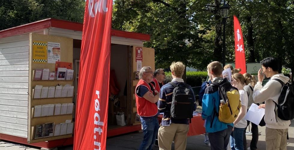 Rødt sin stand plassert i Karl Johan. Flagg fra Rødt i forgrunnen. Ungdommer står rundt.