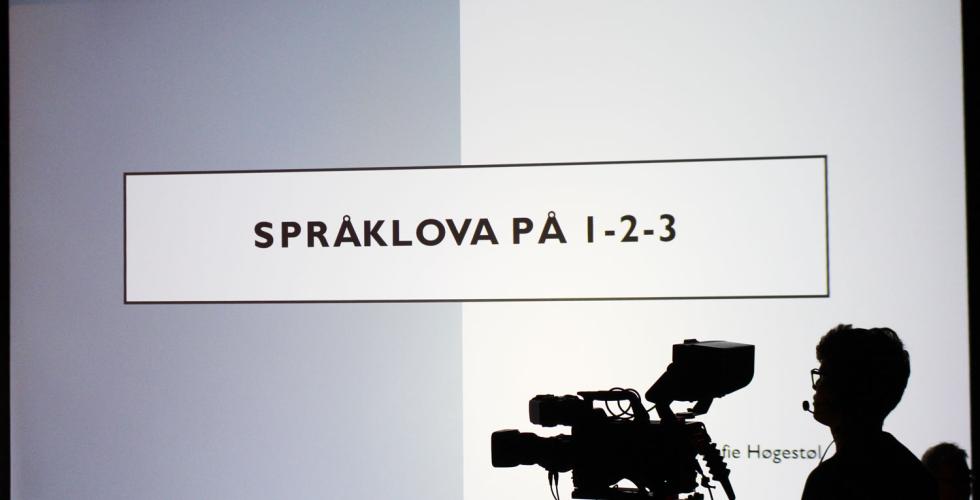 Bilete av framføringa på Språkdagen. Kameramann i siluett på høgre side. 