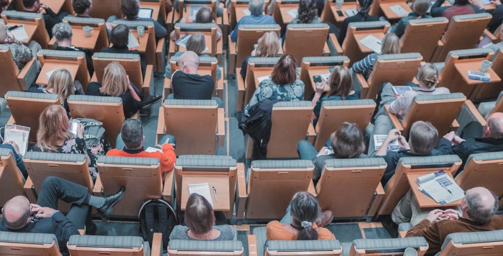 Bilde av studenter som sitter i et auditorium. 