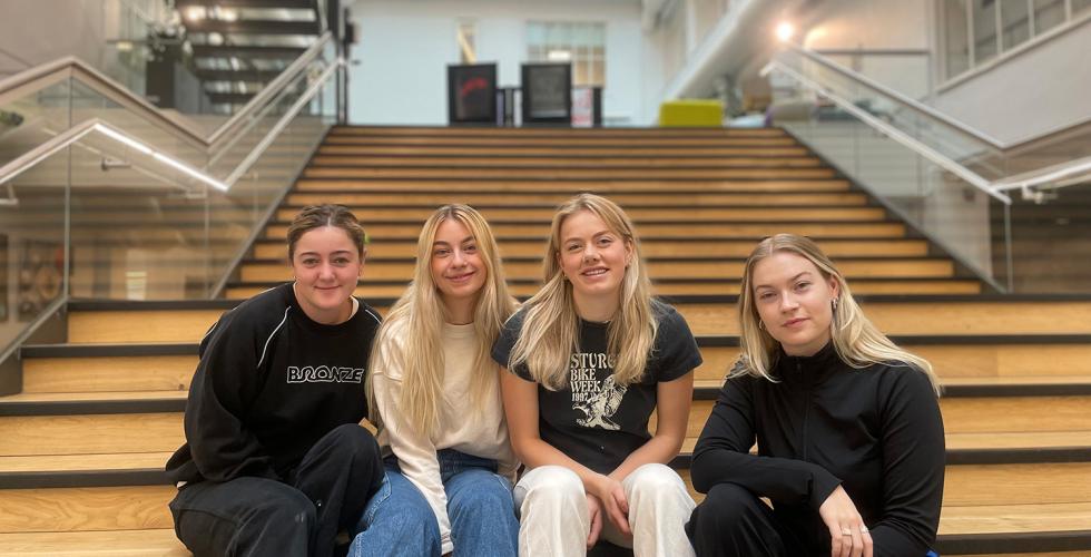 Fire jenter sitter I trappa på Høyskolen Kristiania.