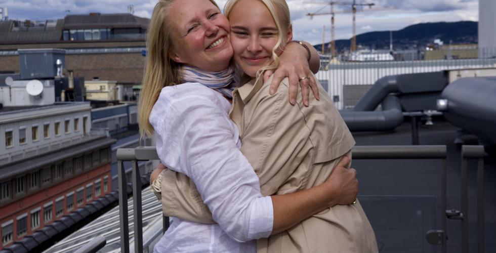 Artisten Thea Marlene og moren omfavner hverandre på en takterasse med utsikt ut over Oslo