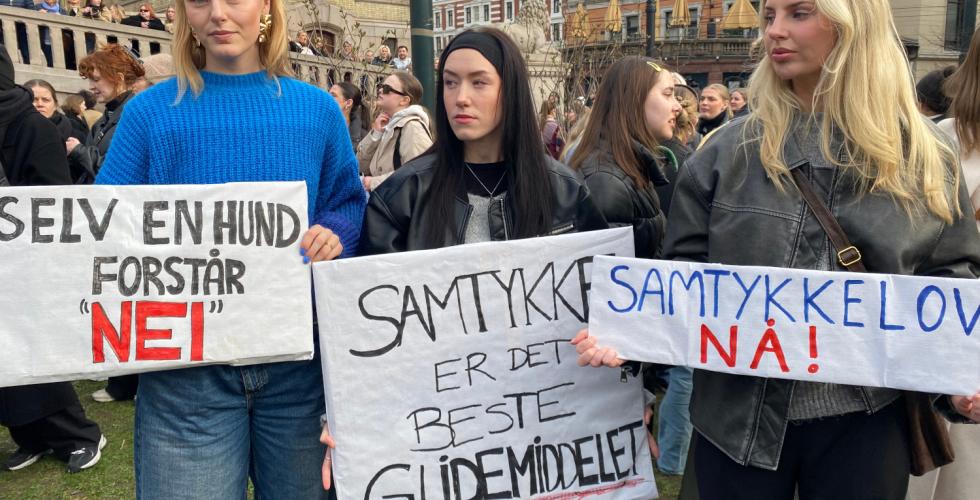 Tre jenter holder skilt på demonstrasjon for samtykkelov.