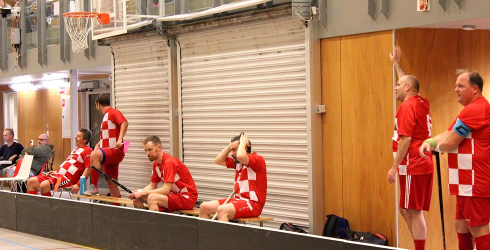 Menn på sidelinjen i en innebandy kamp.