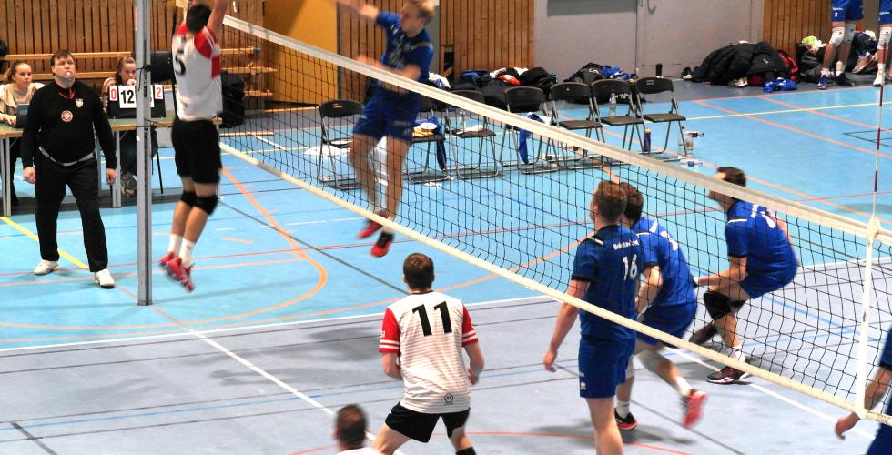 En spiller fra BK Tromsø smasher en volleyball forbi en spiller fra OSI som prøver å blokke.