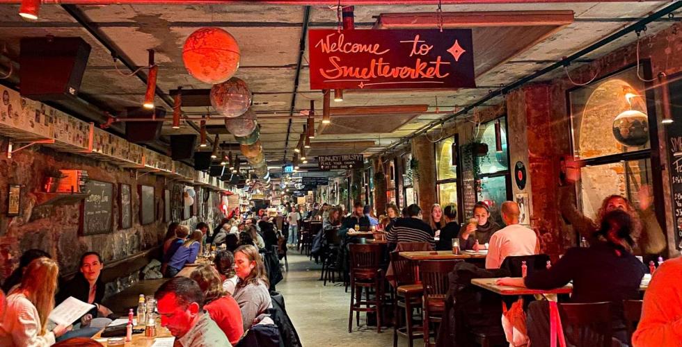 Smelteverket er et sted folk kommer til å være med på musikkbingo. På bildet ser vi mange grupper folk som sitter ved deres bord og prater med hverandre. 