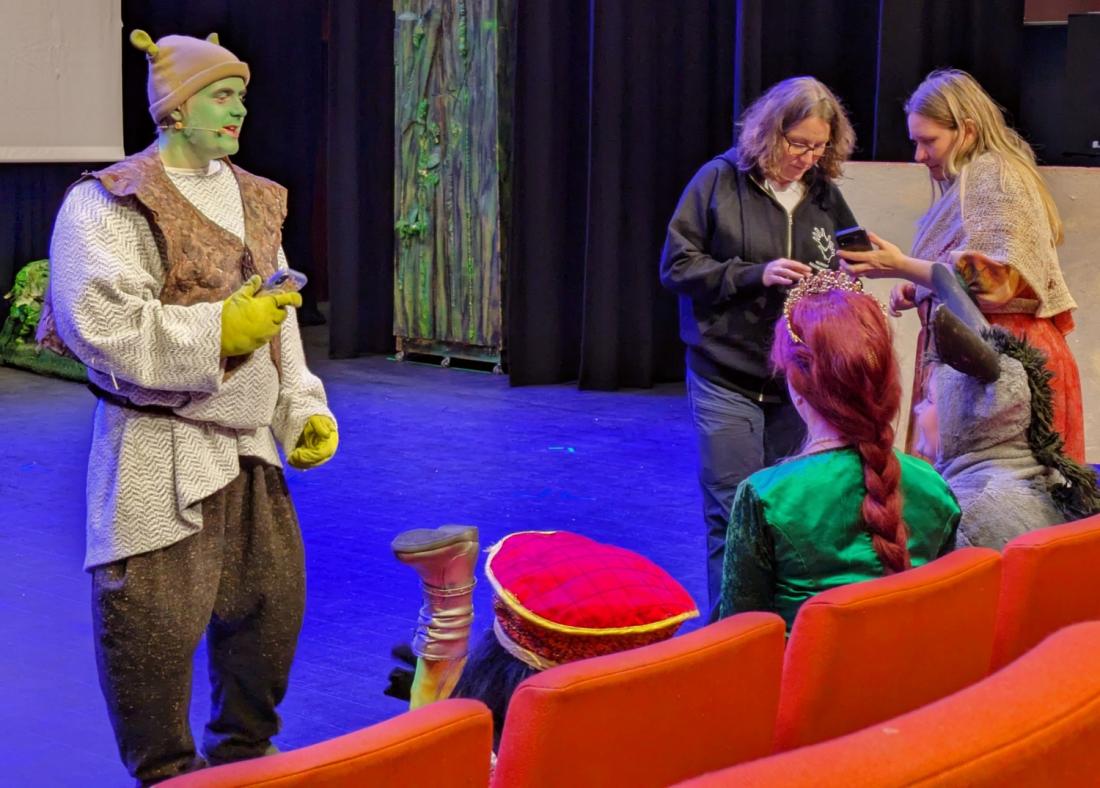 skuespilleren til shrek st&aring;r p&aring; scenen og leser opp fra en mobil