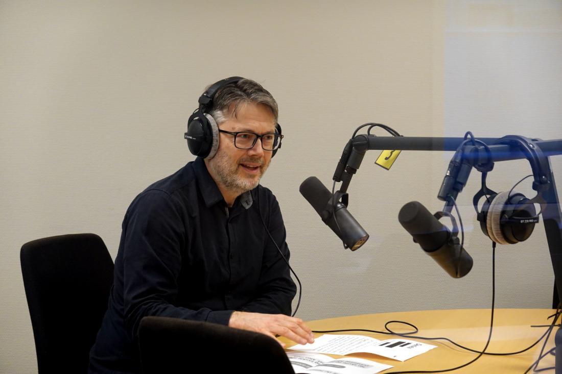 Mann foran mikrofon i lydstudio 