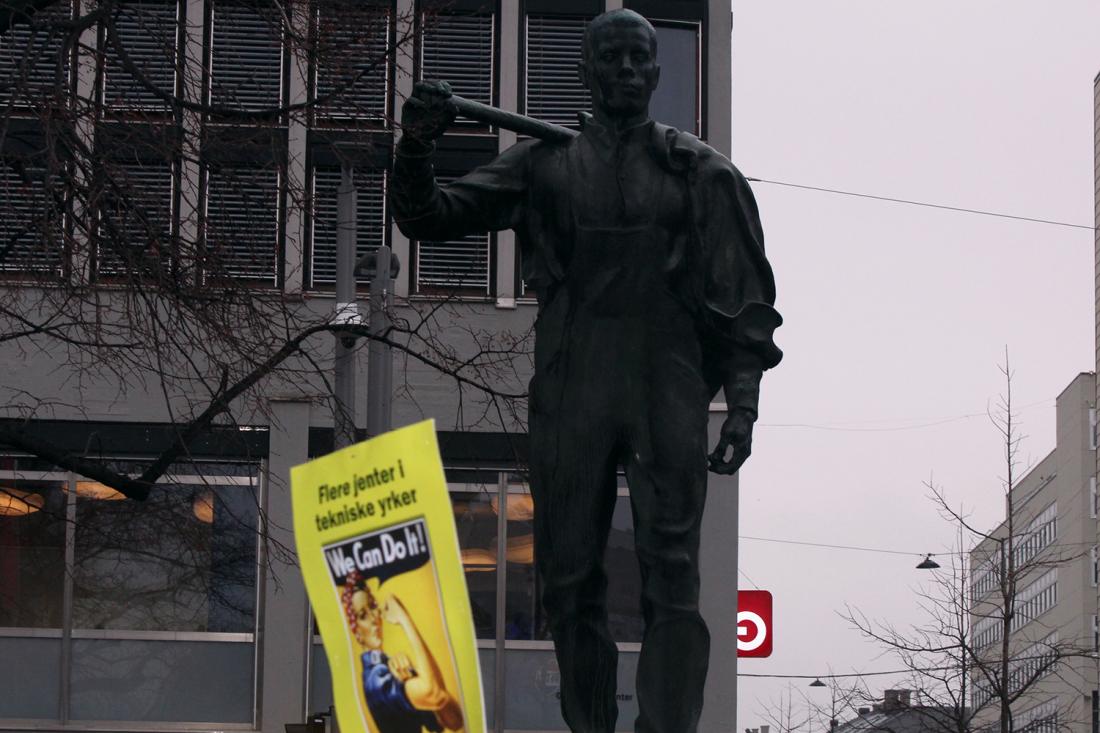 plakat der det st&aring;r "Flere jenter i tekniske yrker, sats p&aring; jenter i yrkesfag" med et bilde av Rosie the Riveter og "we can do it"-slagordet hennes foran statuen av LO-mannen