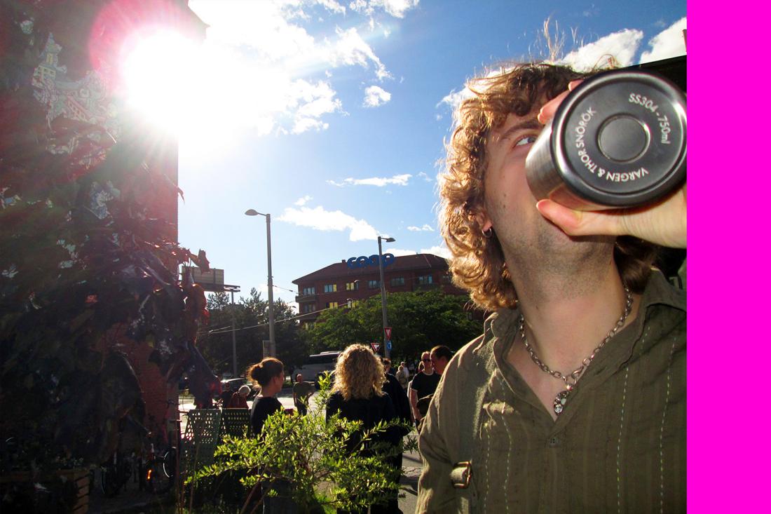 sol skinner direkte i kamera, vi ser en person drikke vann og undersiden av flasken vises 
